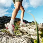 Person wearing SCARPA hiking boots on a rocky trail.