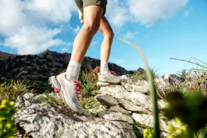 Person wearing SCARPA hiking boots on a rocky trail.