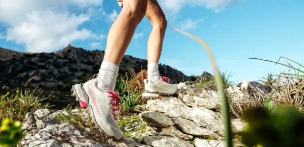 Person wearing SCARPA hiking boots on a rocky trail.